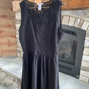 Black sleeveless dress, mid thigh length.